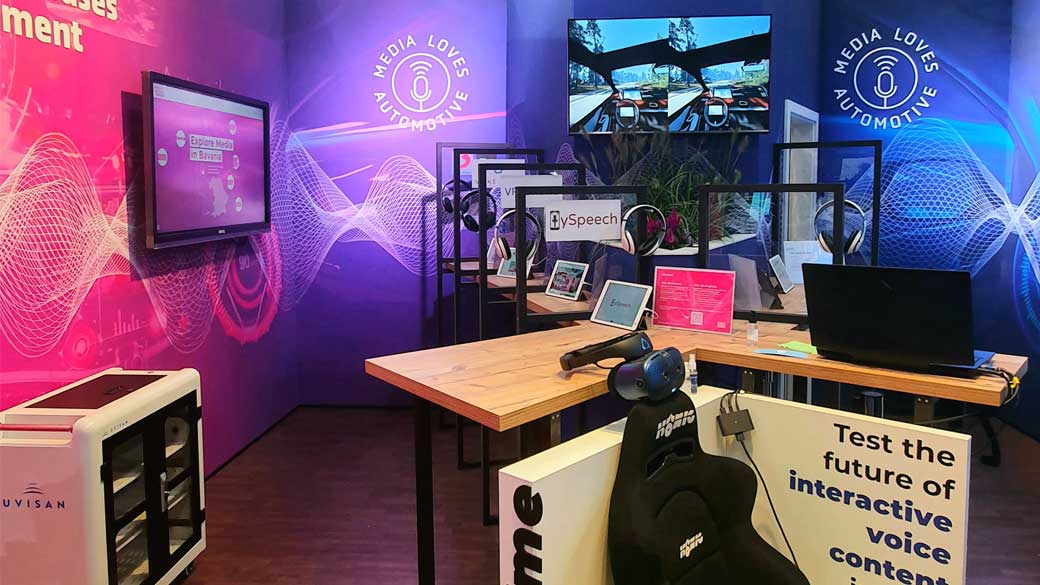 Messestand Media Loves Automotive mit Bildschirmen und Kopfhörer-Hörplätzen auf der IAA Mobility