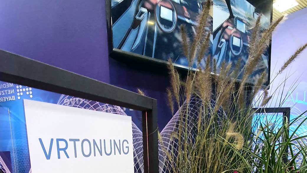 VRTONUNG-Aufsteller vor einem Bildschirm mit 360-Grad-Video auf der IAA Mobility