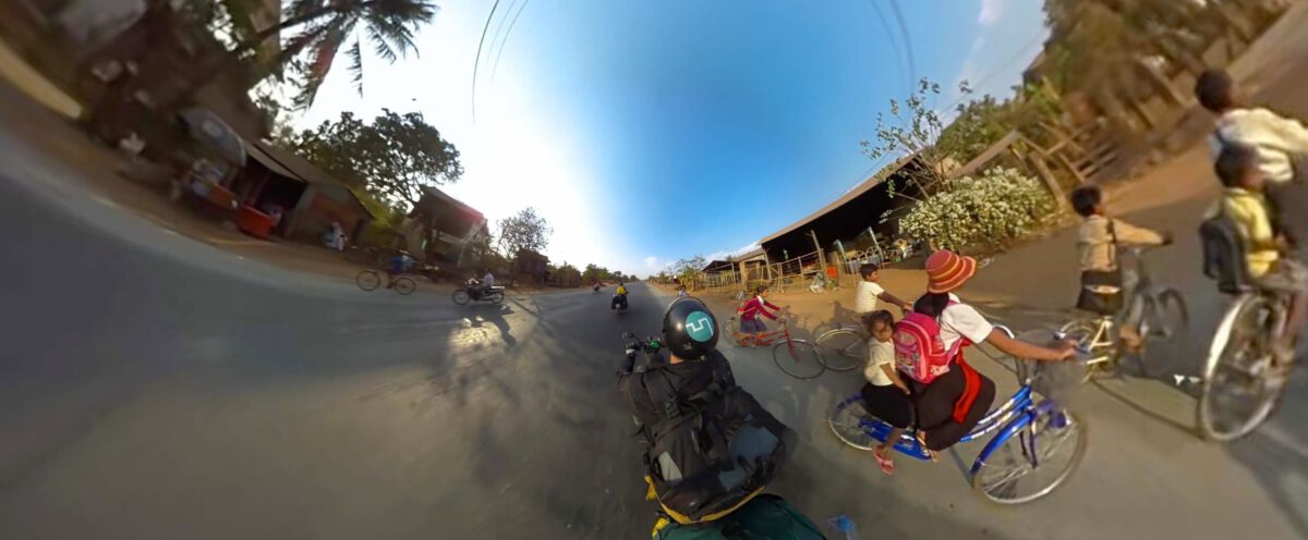 360-Grad-Standbild einer Straße mit Radfahrenden und Mopeds, seitlich verzerrt