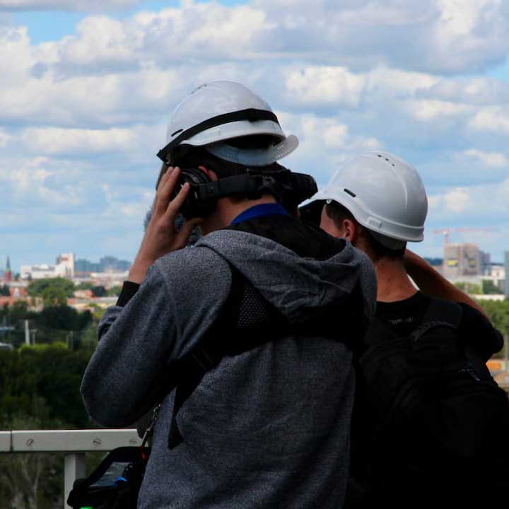 Menschen mit Schutzhelmen blicken über die Stadt