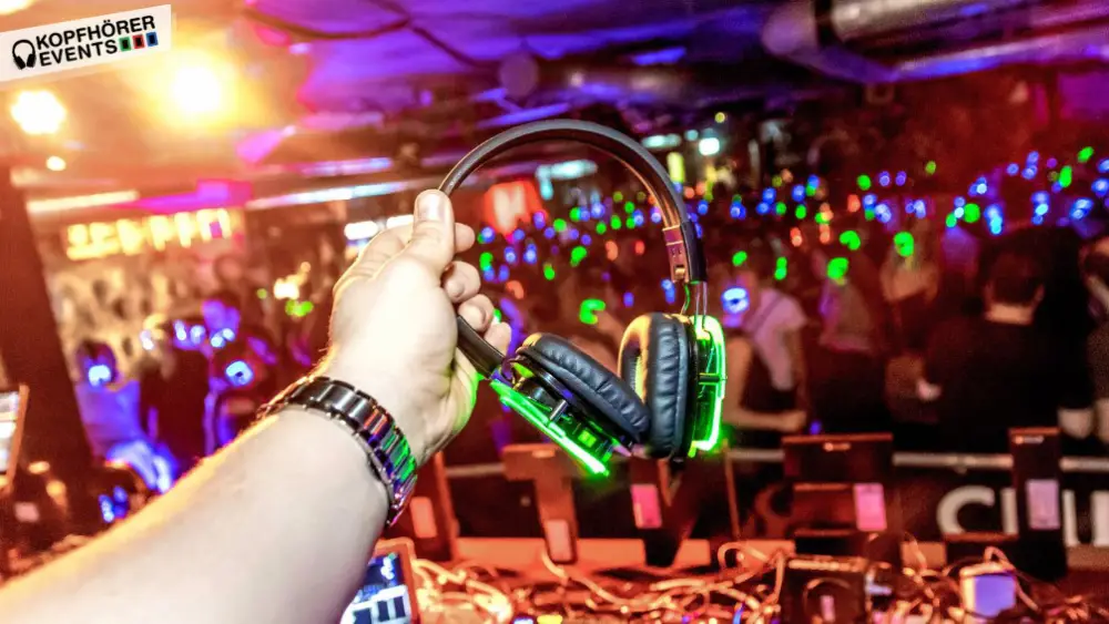 Hand holding a pair of glowing headphones at a silent disco