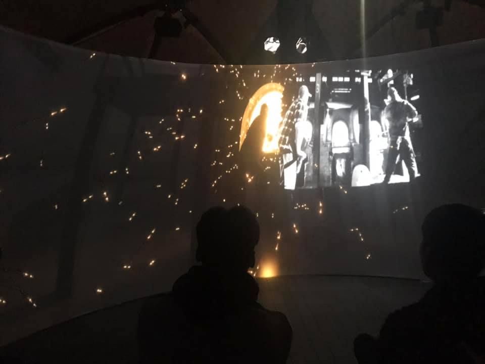 Publikum im Igloo-Projektionszylinder in Sheffield, Funken der Glasproduktion fliegen über die 360-Grad-Leinwand