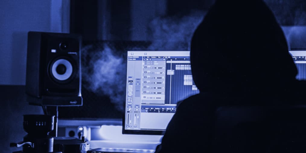 Person an einem Studioarbeitsplatz mit Monitorlautsprecher und DAW auf dem Bildschirm