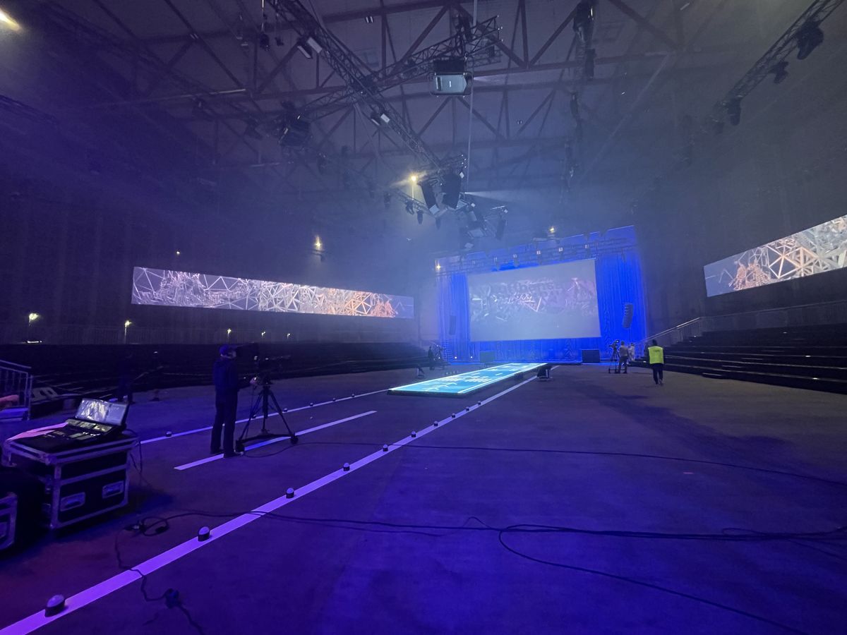 Beleuchteter LED-Runway quer durch den Hangar, dahinter die große Leinwand der Show