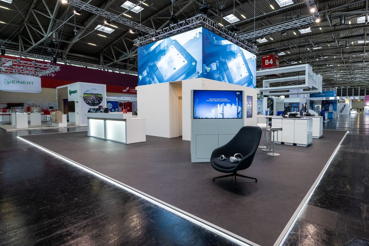 Interaktiver Messestand von Physik Instrumente mit Bildschirmwand und Exponaten