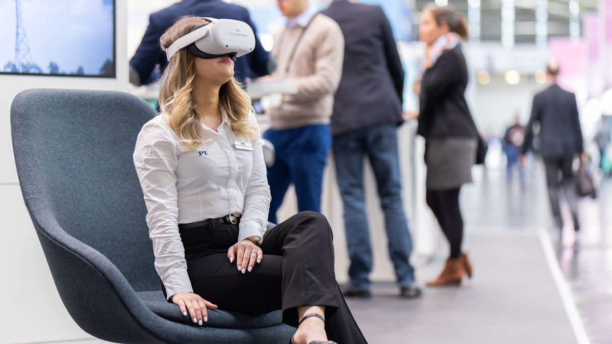 Besucherin mit VR-Brille im Sessel am Messestand von Physik Instrumente