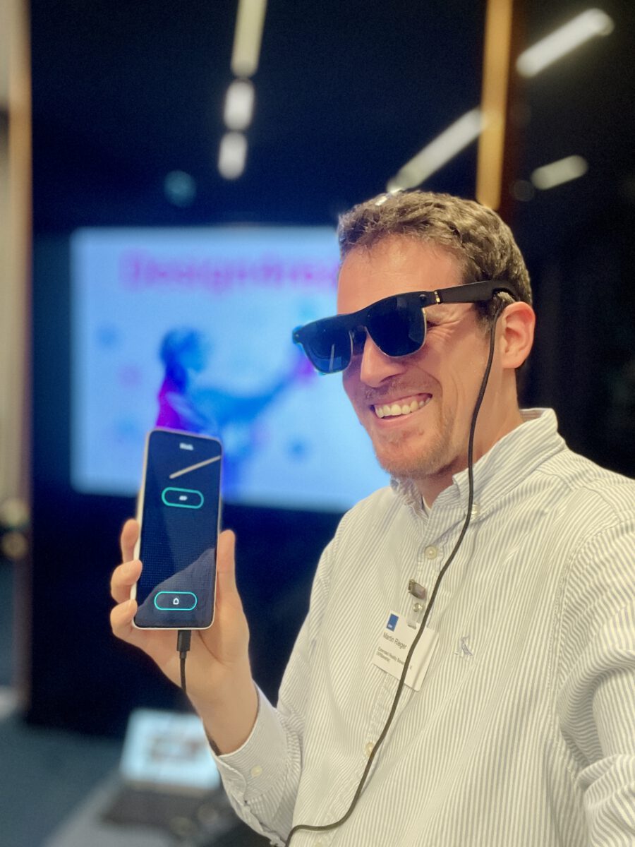 Martin Rieger wearing XREAL smart glasses, smiling, with the companion app open on his phone