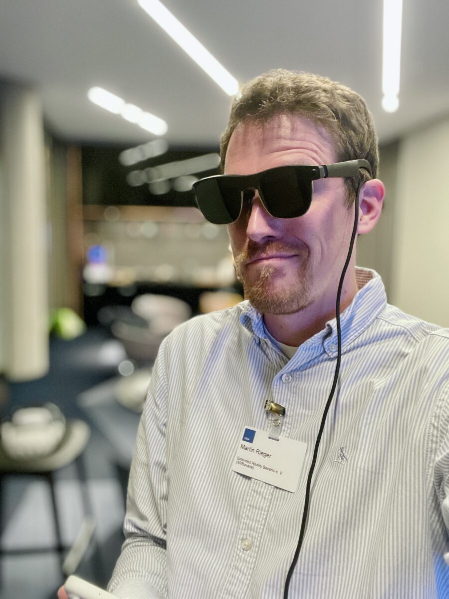 Martin Rieger wearing XREAL smart glasses at an XR Bavaria event, testing open-ear audio