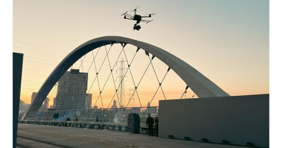 Camera drone in flight in front of the arch of a bridge in Los Angeles at sunset