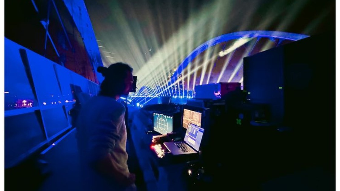 Person at the control desk in front of a bridge in Los Angeles during the night light show with laser beams