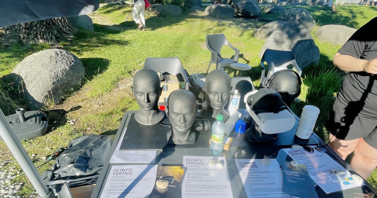 Tisch mit mehreren VR-Brillen auf Puppenkoepfen, daneben Infoblaetter der Installation