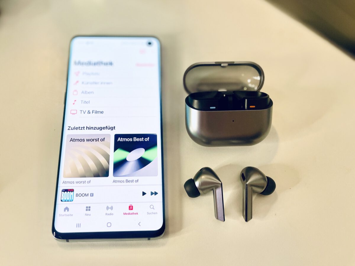True wireless earbuds next to a spatial audio app on a smartphone