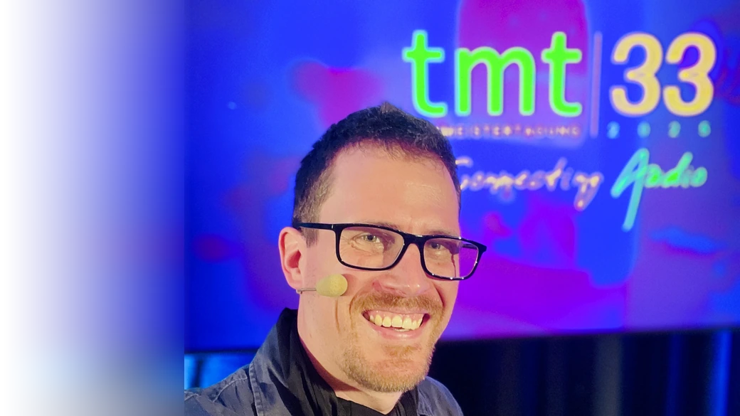 Martin Rieger with headset microphone in front of the tmt33 screen at the 33rd Tonmeistertagung in Düsseldorf