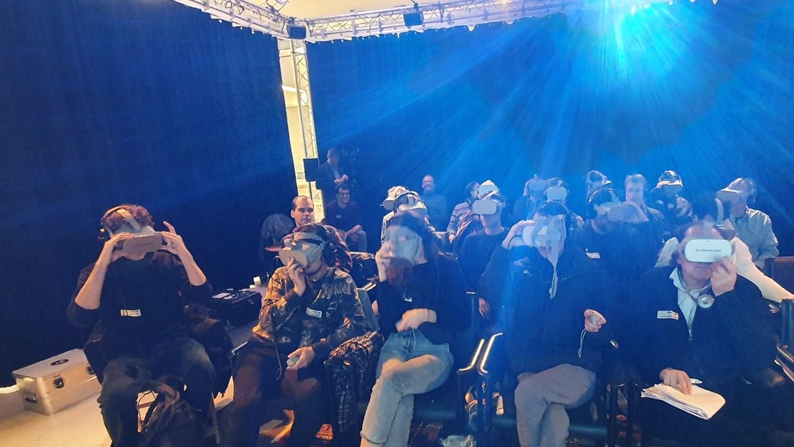 Audience wearing VR headsets in rows of chairs at a shared VR film screening