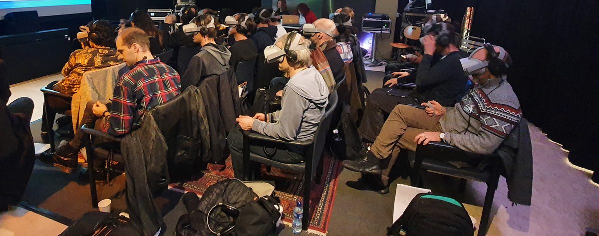 Room with an audience wearing VR headsets and headphones